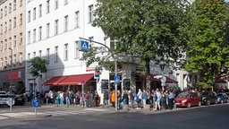 Interessenten stehen wartend in einer Schlange auf dem Gehweg einer Wohnung
