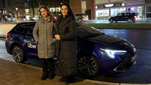 Fahrerin Maria Rezaei und Fahrgast Paula Dominges vor dem Auto 