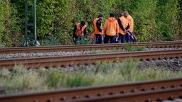 Mitarbeiter der Deutschen Bahn stehen am Rande der Bahnstrecke Köln-Düsseldorf.