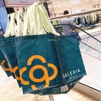 Taschen mit dem Firmen-Logo von Galeria hängen in einer Filiale