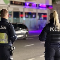 Zwei Polizisten stehen nachts in der Euskirchener Innenstadt mit dem Rücken zur Kamera auf einer Straße. Im Hintergrund ist eine Shisha-Bar zu erkennen.