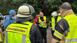 Mehrere Feuerwehrleute stehen gemeinsam im Regen und besprechen das gemeinsame Vorgehen