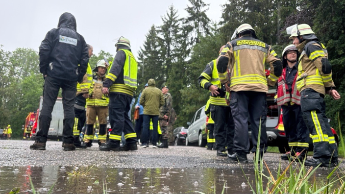 Gleich mehrere Einsatzkräfte der Feuerwehr stehen während der Übung im Regen.
