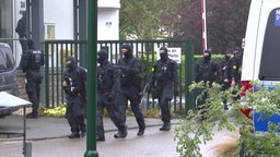 Polizeibeamte mit Sturmhauben laufen durch das Tor der Justizvollzugsanstalt Euskirchen