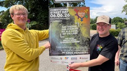 Liebe sei stärker als Hass, steht auf dem Plakat, das zwei Organisatoren hochhalten