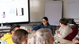 Eine Gruppe von Menschen sitzt an einem Tisch und tauscht sich aus. 