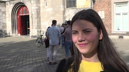 Die Studentin mit den schwarzen Haaren trägt ein gelbes T-Shirt