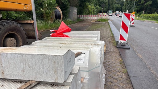 weiße große Bordsteinkanten mit taktilen Elementen liegen an einer Baustelle bereit