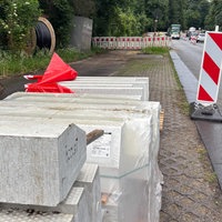 weiße große Bordsteinkanten mit taktilen Elementen liegen an einer Baustelle bereit