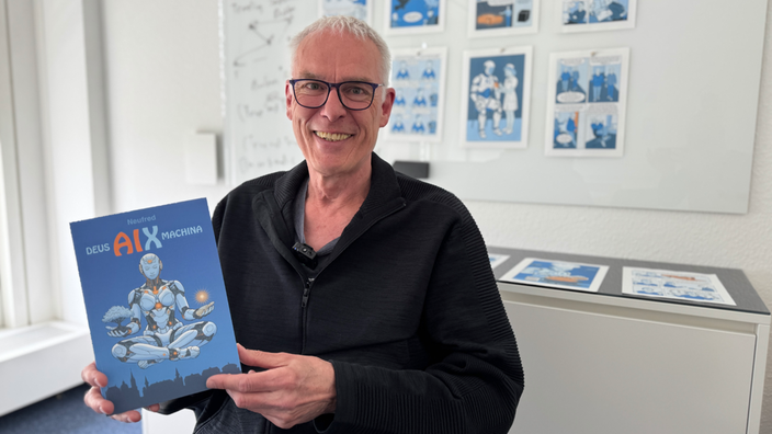 Comiczeichner Alfred Neuwald hält sein Comic in die Kamera
