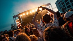 Publikum beim Festival vor der Bühne, im Vordergrund ein Zuschauer, der ein Herz mit seinen Händen zeigt