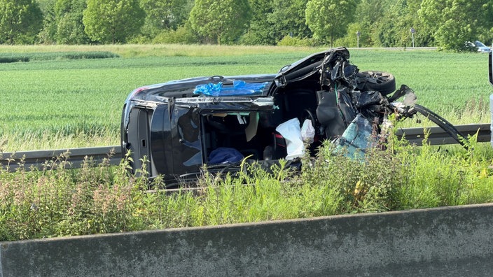 ein schwarzes Auto liegt verbeult auf der Seite mit einem offenen Dach 