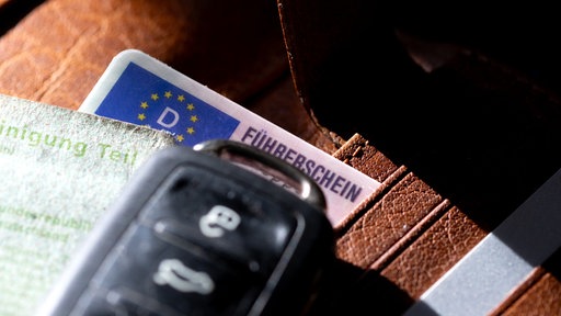 Ein Autoschlüssel und ein Führerschein liegen auf einer Geldbörse