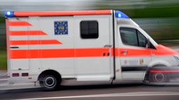 Ein Krankenwagen fährt mit Blaulicht über eine Straße.