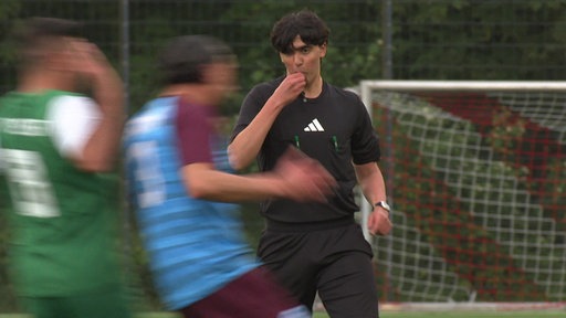 ein Schiedsrichter pfeift zwei Fußballspieler ab
