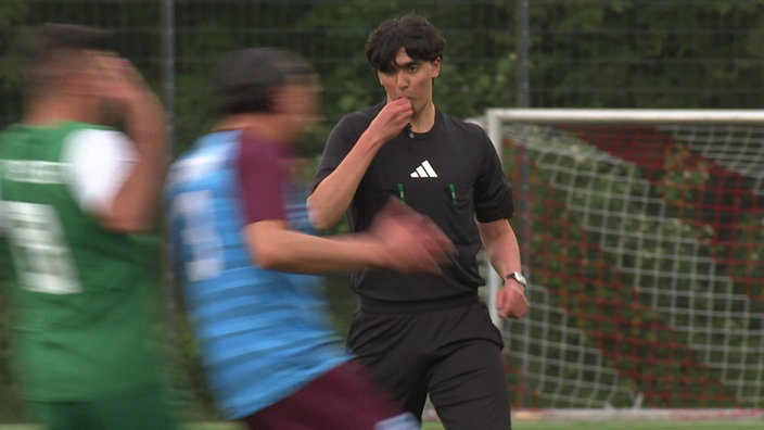 ein Schiedsrichter pfeift zwei Fußballspieler ab