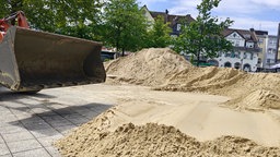 Ein Bagger schaufelt Sand auf den Kirchplatz in Heiligenhaus