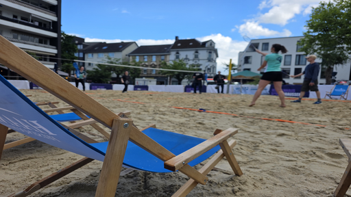 Liegestuhl, Sand und Personen die Federball spielen