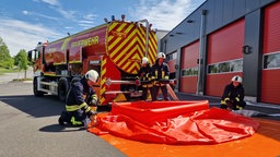 Einsatzkräfte bauen ein Sammelbecken für Wasser am Fahrzeug auf.