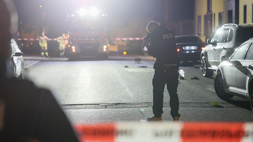 Ein Polizist steht auf der Straße und fotografiert mögliche Spuren
