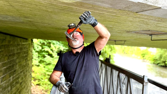 Bauingenieur macht Klopfprobe an Brückenbauwerk