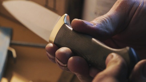 Messerhersteller hält Messer in Hand