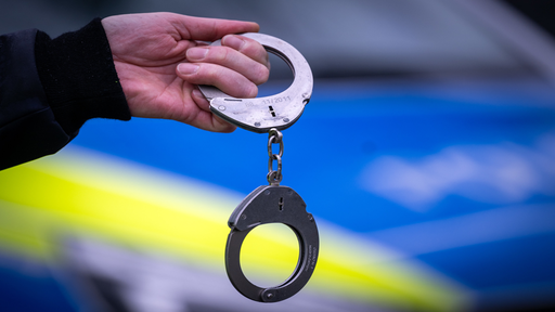 Polizei Auto und Person die Handschellen festhält