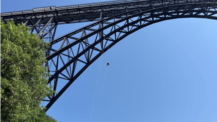 Ein Mann seilt sich von einer Brücke ab