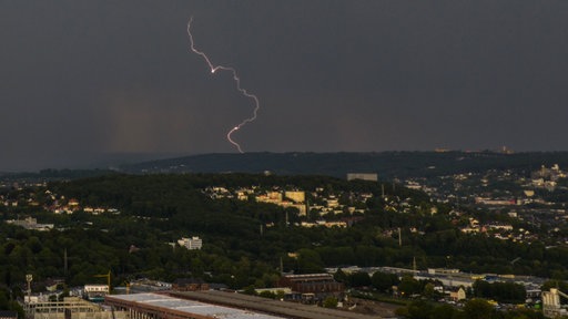 Eine Panoramaaufnahme zeigt einen Blitz am dunklen Himmel über Wuppertal