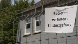 Zu sehen ist ein Schild "Betreten verboten! Einsturzgefahr!", das am Zaun hängt.