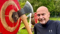 Doppelaxt steckt in Zielscheibe. Davor der 1. Vorsitzende Guido Klees