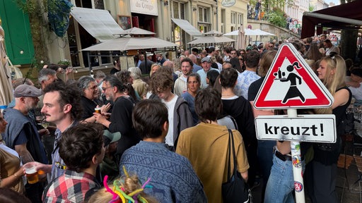 Volle Straße beim Luisenfest in Wuppertal. Im Vordergrund ein Verkehrsschild, das auf kreuzende Service-Kräfte hinweist
