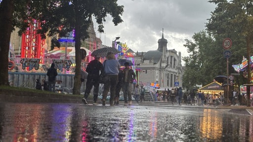 Menschen laufen mit Regenschirmen durch den Regen auf dem Bielefelder Stadtfest