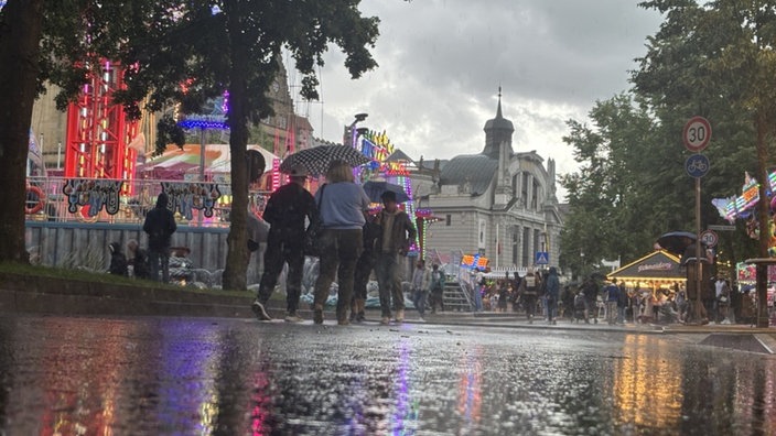 Menschen laufen mit Regenschirmen durch den Regen auf dem Bielefelder Stadtfest