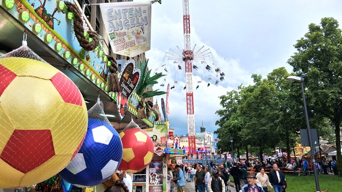 Menschen laufen vor dem Kettenkarussel auf dem Leinewebermarkt entlang