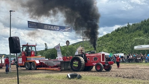 Ein Traktor, aus dem schwarzen Rauch qualmt.