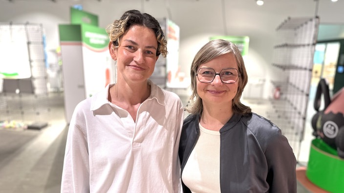 Jule  Klemm und Silke Zimmermann stehen inmitten der Austellung in Dortmund und blicken in die Kamera