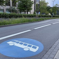 Eine mehrspurige Straße, auf der rechten Spur ist ein großes Symbol mit einem Bus