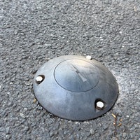 Auf dem Asphalt ist eine kleine runde Scheibe eingelassen