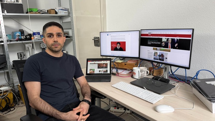Foad Gholinejad sitzt an einem Computer und blickt in die Kamera