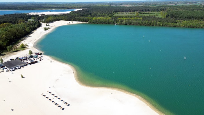 Der Silbersee II aus der Luft bei sonnigem Wetter mit weißem sandstrand und blauem Wasser