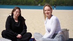 Zwei junge Frauen sitzen auf dem Sandstrand am Silbersee II