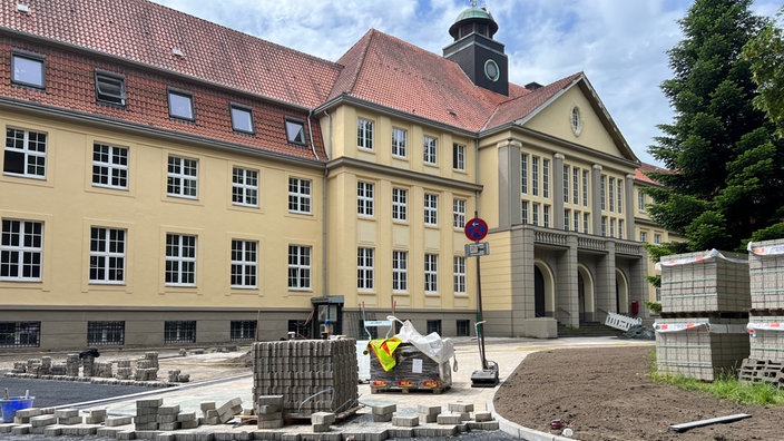 Vor dem eindrucksvollen Rathaus wird der Weg neu gepflastert. Die Arbeiten sind in vollem Gange, viele der Steine liegen noch gestapelt auf der Baustelle.