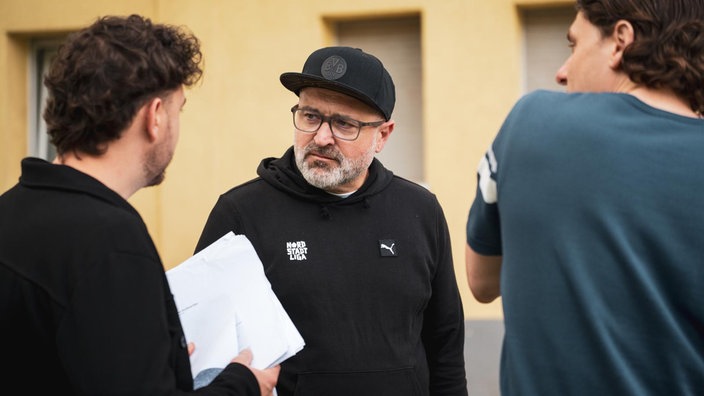 Mann hört zwei Menschen zu