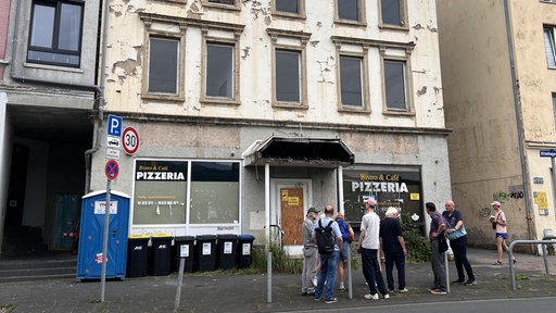 Die Gruppe an Forschern steht vor einem heruntergekommenen Gebäude in Hagen.