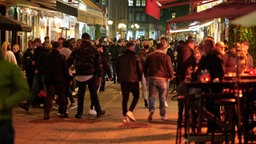 Der Blick in eine Straße in der Düsseldorfer Altstadt am Abend, viele Menschen sind unterwegs
