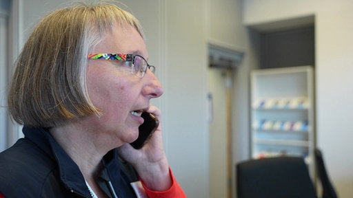 Eine Frau mit mittellangen grauen Haaren telefoniert mit einem Handy