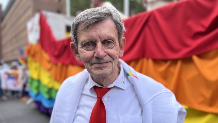 Der Organisator Kalle Wahle steht vor einer Regenbogenflagge