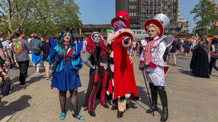 Vier Freunde stehen in bunten Cosplays auf dem Messegelände in Düsseldorf bei der Dokomi