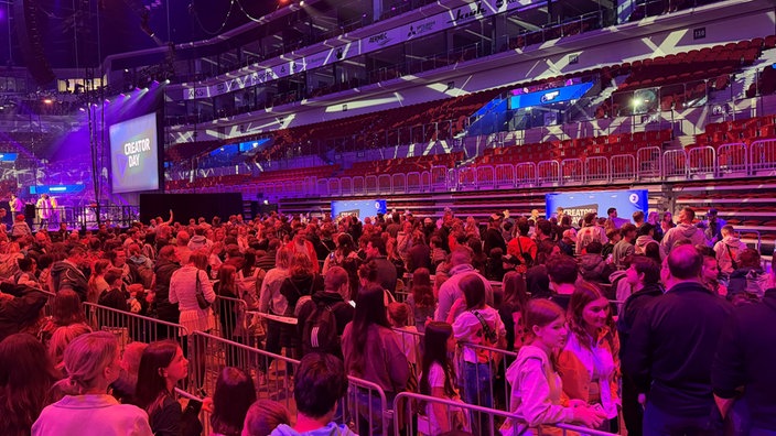 Reihenweise sthen junge Menschen in einer Halle an